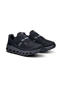 Baskets de course noires imperméables avec une tige texturée, des accents réfléchissants et une semelle rembourrée avec des trous de ventilation.