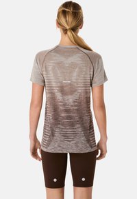 Koszulka sportowa z krótkim rękawem w jasnobrązowym kolorze z teksturowanym, gradientowym wzorem i perforacjami, w zestawie z dopasowanymi, ciemnobrązowymi szortami.