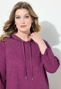 Viininpunainen pitkähihainen huppari, jossa on teksturoitu pinta. Hupparissa on säätönyöri ja edessä on ripoteltuja helmikoristeita.