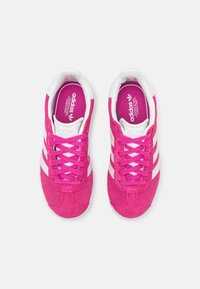 Vaaleanpunaiset mokkanahkakengät valkoisilla raidoilla, joissa nyöritys ja pehmustetut kieliset osat. Sisäpuolella vaaleanpunaiset pohjalliset, joissa Adidas-logo.