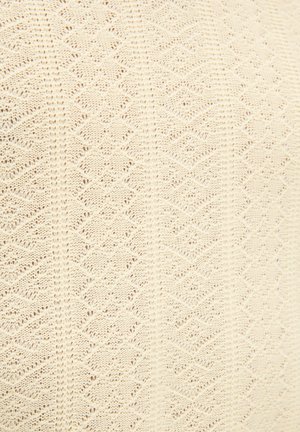 Crèmekleurige gebreide stof met een herhalend ruitpatroon en een gestructureerde afwerking, met open en gesloten steekvariaties.