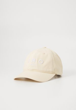 Beige baseball cap with curved brim and white embroidered text "IRO PARIS" on the front, shown against a white background.
