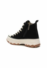 Sneaker alte in suede nero con lacci crema, una cerniera laterale e una suola intermedia bianca spessa con dettagli del battistrada marroni.