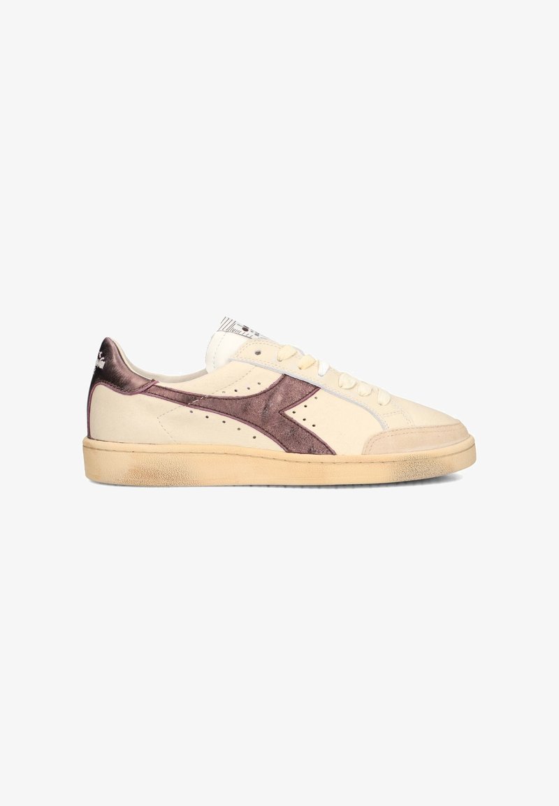 Low-top cream sneaker with metallic purple side logo, lace-up front, and slightly worn beige sole, angled left on white background.