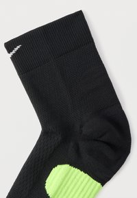 Μαύρη αθλητική κάλτσα με υφή σχεδίου, ριμπ μανσέτα και φωτεινή πράσινη λεπτομέρεια στο πλάι. Κεντημένο λογότυπο κοντά στην κορυφή.