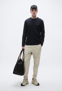 Hosszú ujjú tengerészkék ing, bézs nadrág, fekete vállpántos táska és szürke sportcipő fekete részletekkel; egyszerű kialakítás, semleges színek, alkalmi öltözet.