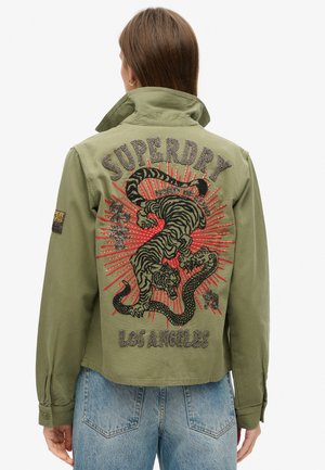 Kurtka w kolorze oliwkowej zieleni z haftowanym wzorem tygrysa i czerwonymi akcentami na plecach, z tekstem "Superdry" i "Los Angeles" w metalizowanej nici.
