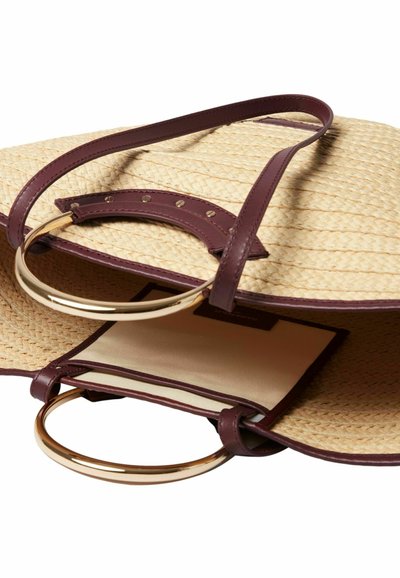Sac fourre-tout en paille tissée avec des accents en cuir bordeaux, anneaux ronds en métal doré, et un compartiment intérieur beige. Surface texturée.
