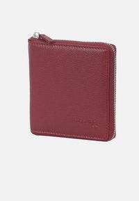 Portafoglio in pelle rossa con finitura texturizzata, caratterizzato da una chiusura con zip superiore e un logo in rilievo sul davanti. Forma quadrata, design minimalista.