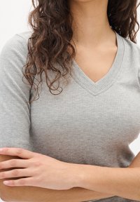 Grå rutig V-ringad topp med korta ärmar, texturerat tyg, figurnära passform och subtil V-formad halsringning.