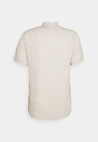 Camicia in lino leggera a maniche corte di colore beige chiaro, con colletto alla cinese, spalla posteriore e orlo dritto. Tessuto morbido con un leggero intreccio.