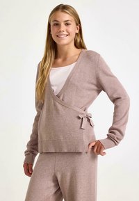 Lyserød strikket cardigan med V-hals, ribbede manchetter og bindelukke i taljen, kombineret med matchende loungebukser. Glat tekstur.