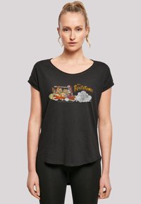 Svart T-skjorte med oppbrettede korte ermer, med et fargerikt «The Flintstones»-motiv på forsiden, laget av mykt stoff.
