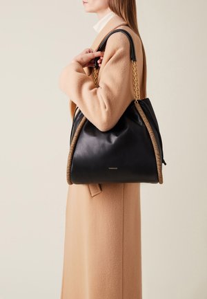 Schwarze Leder-Tote mit gewebten beigen Akzenten und goldenen Kettenhenkeln, die ein lässiges Design für zusätzlichen Textur bietet.