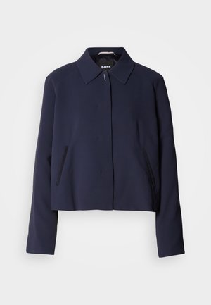 Navy blue cropped jacket with a pointed collar, front button closure, side pockets, and a smooth fabric finish. Logo displayed inside.