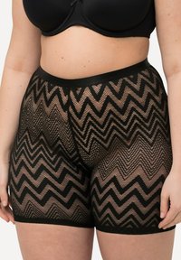 Zwarte kantshorts met een zigzagpatroon, een elastische tailleband en een semi-transparante textuur die tot halverwege de dij gevallen zijn.