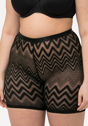 Zwarte kantshorts met een zigzagpatroon, een elastische tailleband en een semi-transparante textuur die tot halverwege de dij gevallen zijn.