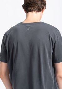Grijze t-shirt met korte mouwen van zachte stof en een relaxte pasvorm. Heeft een subtiele kleurenafdruk van een schaar op de achterkant van de hals.
