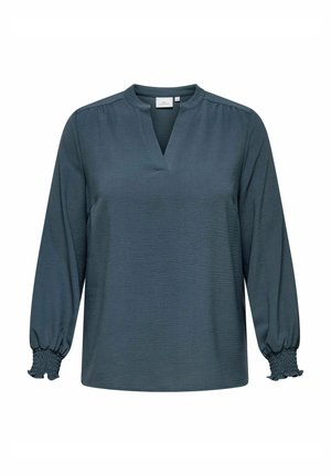 Tumman teal-värinen bluse kevyehkössä kankaassa, jossa on V-aukko, rypistetyt olkaharjat ja rento malli. Pitkät hihat elastisilla resoreilla. Rakenne on teksturoitu.