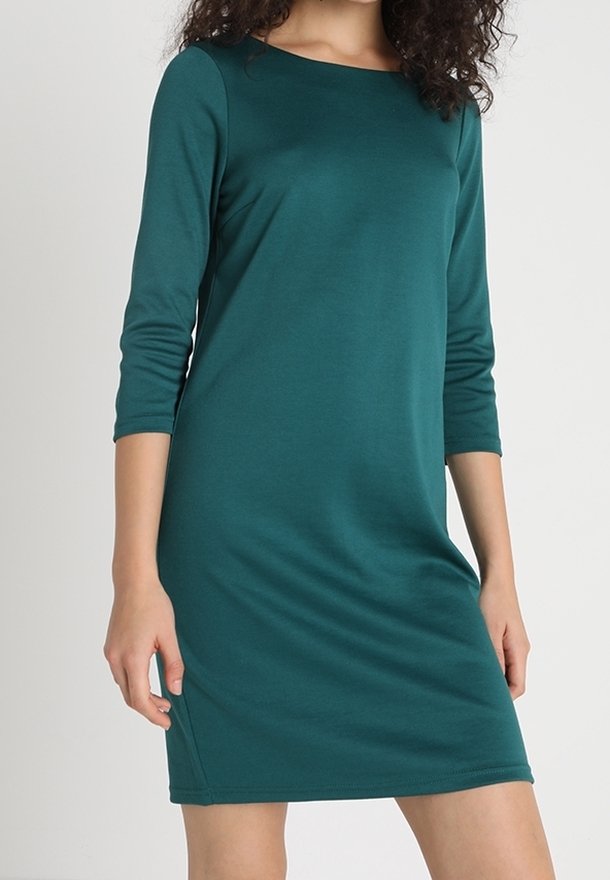 Teal långärmad klänning i mjukt, stretchigt tyg, med en enkel rund halsringning och en figurnära silhuett som vidgar sig något vid fållen.