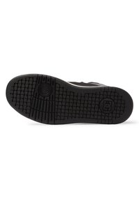 Black rubber sole with textured tread and circular logo. Features horizontal and vertical grooves for traction. Lower profile design.