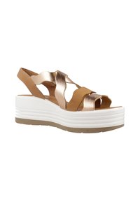 Sandali marroni e metallici con molteplici cinghie incrociate, una suola piatta bianca con bande testurizzate, caratterizzati da una forma sagomata e design slip-on.