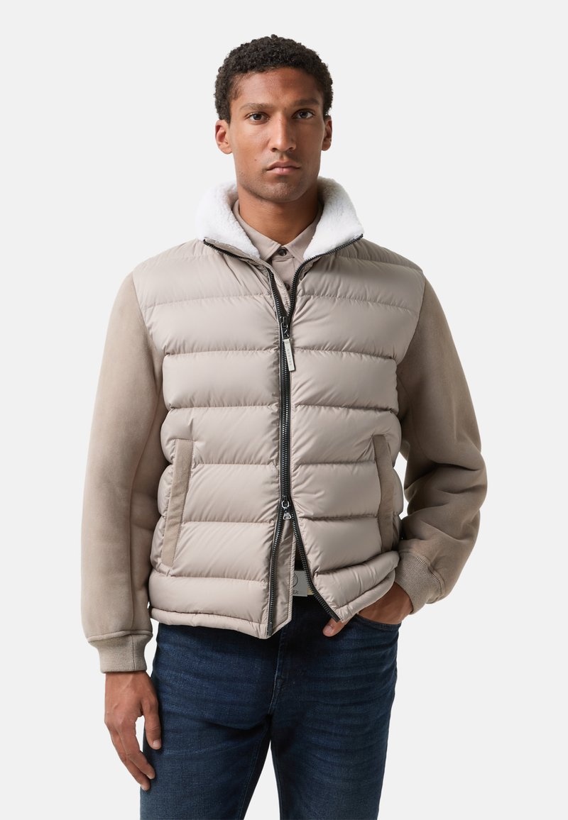 Pufferjakke i beige med lynlås foran, kunstpelskrave og glat stof med et dunfyldt design. Båret over en skjorte med krave.