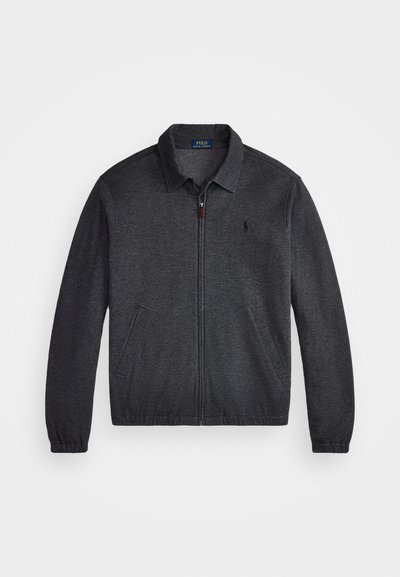 Tumši pelēks cardigan ar rāvējslēdzēju priekšā, apkakles dekoltē un divām sānu kabatām. Iezīmējas ar elastīgām piedurknēm un mazu logo uz krūts.