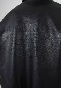 Černá kožená bunda s reliéfním motivem vintage závodního auta a zeměkoule, s nápisem „Prohibited Racing Club“ na zádech.