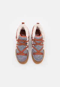 Botas de fieltro grises con correas naranjas, forro de piel sintética y suelas de goma marrón. Cuentan con una punta redondeada y detalles de hebilla ajustable.