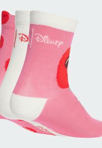 Calzini Disney rosa con pois rossi e faccia di un personaggio dei cartoni, con bordo a coste bianco e logo sulla suola. Tessuto morbido ed elastico.