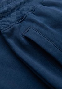 Donkerblauwe stof van joggers met een geribbelde tailleband, een gladde textuur en een zijzak met platte naden.