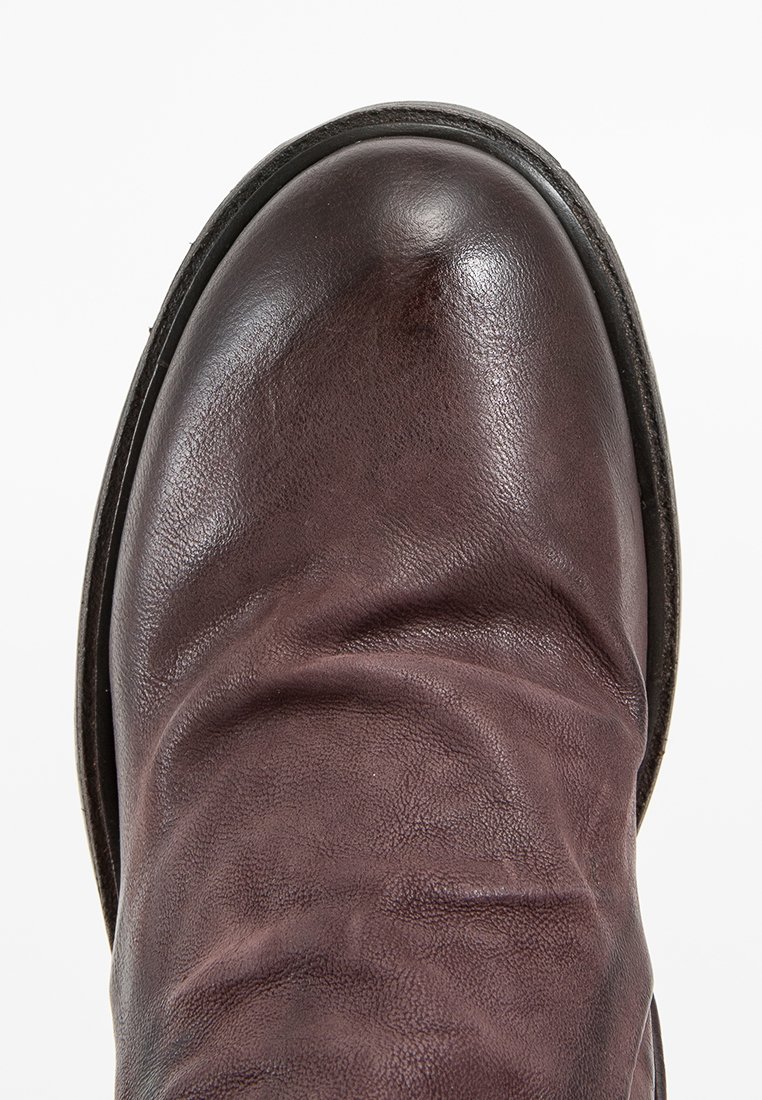 Smeeđi kožni čizmi s zaobljenim vrhom, teksturiranom površinom i vidljivim nabora. Čvrst potplat s suptilnim detaljima šivanja oko ruba.