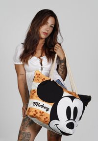Gran bolsa tote hecha de tela, con un diseño de Mickey Mouse en negro, blanco y naranja. Incluye asas de cuerda y cremallera.