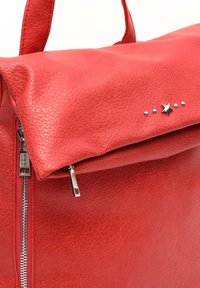 Rdeča usnjena torba z embossed površino, zadrgo in zadevo z zvezdo ter kovinskimi žebljički na pokrovu.