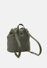 Olivgrön tygryggsäck med justerbara axelremmar, rundad topp och guldfärgade detaljer, med en central metallring.