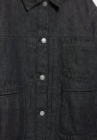 Svart denimjacka med krage, silverfärgade tryckknappar och två framfickor. Har en strukturerad tyg och rak passform.