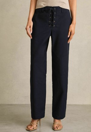 Pantaloni blu navy con lacci sul davanti, dotati di occhielli in metallo e una vestibilità comoda. Realizzati in un materiale resistente con cuciture laterali.