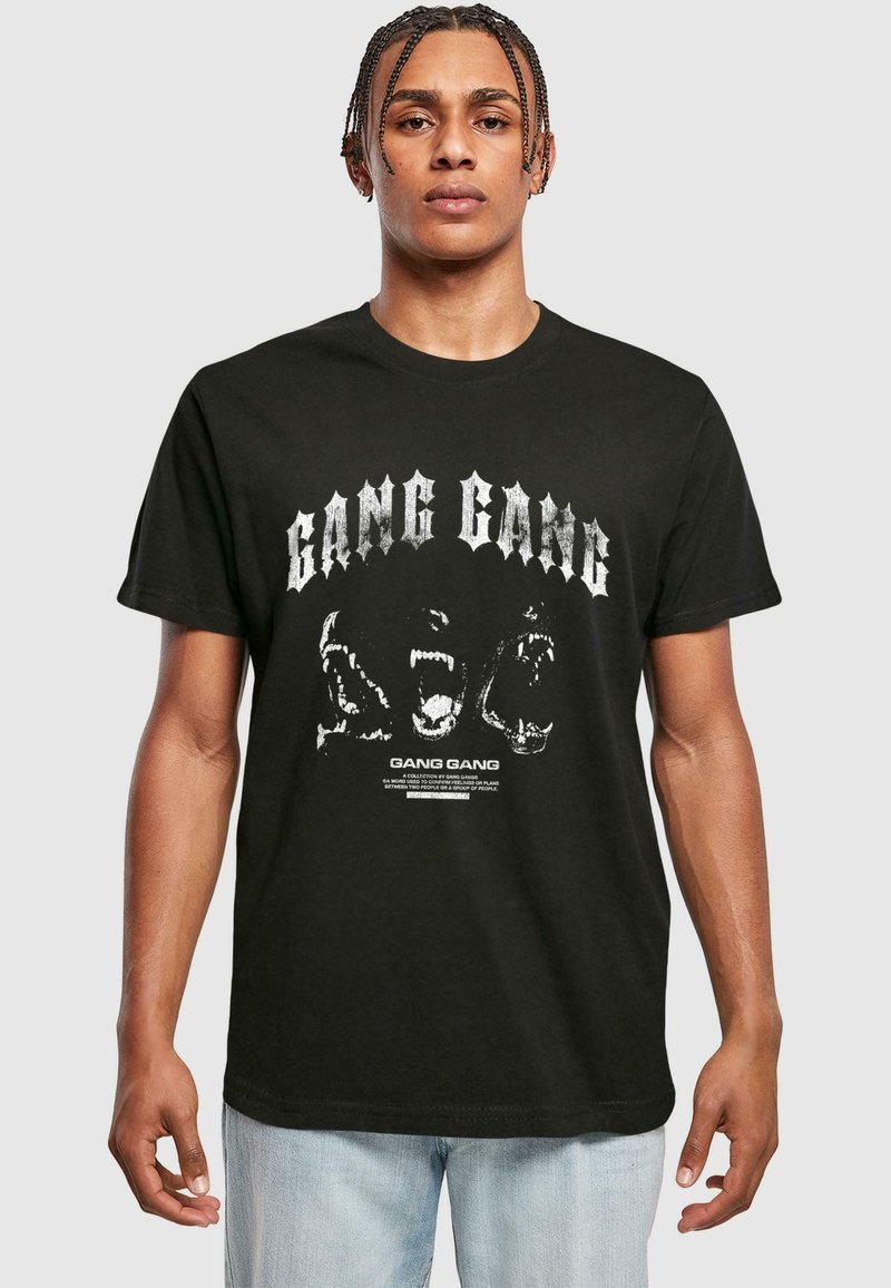 Juodas medvilnės marškinėliai su ryškiu baltu užrašu "GANG GANG" ir grafiniais piešiniais. Trumpomis rankovėmis, apvaliu kaklu ir standartine forma.