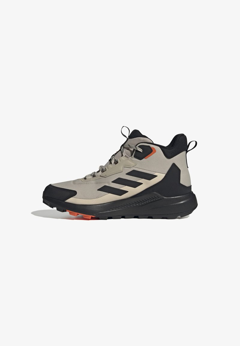 Chaussure de randonnée légère en beige et noir avec un tissu texturé, accents orange et semelle noire robuste. Elle dispose d'un design à lacets et de languettes de traction.