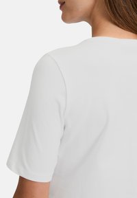 Hvid kortærmet t-shirt med rund udskæring, glat tekstur og en afslappet pasform, der viser ryg- og skulderpartiet.
