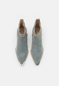 Gray suede ankle boots with pointed toes, decorative studs along the collar, and metallic accents on the toe. Flat heel design.