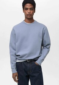 Felpa azzurra chiara realizzata in tessuto misto cotone. Presenta un collo rotondo e polsini a coste. Abbinata a jeans in denim scuro.