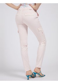 Roze cargobroek met een slim fit, voorzien van twee achterzakken en cargozakken aan de zijkanten, gecombineerd met turquoise hoge hakken.