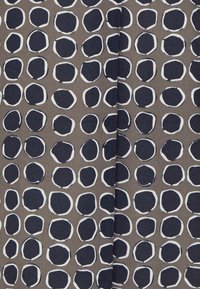 Tyg med en brun bakgrund och jämnt fördelade marinblå och vita cirkulära mönster. Ytan är slät med en subtil lyster.