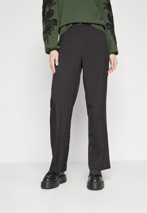 Black tailored trousers with a straight fit, polished fabric, front pockets, and a subtle sheen; paired with a textured green sweater.
