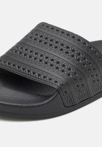 Black rubber slide sandal featuring textured, patterned straps and a contoured footbed for comfort. Smooth finish with a solid sole.