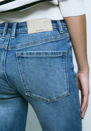 Jeans in denim blu sbiadito con vita alta, dotati di tasche posteriori, etichetta in pelle marrone con "D14" in vita e dettagli di cucitura.