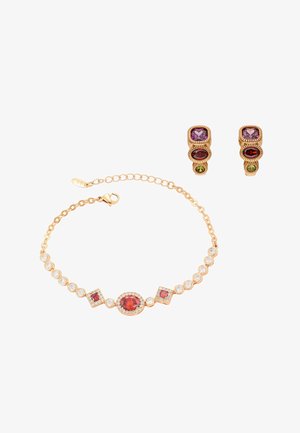 Pulsera de oro con piedras preciosas rojas y transparentes, junto con pendientes de oro a juego con piedras preciosas moradas, rojas y verdes sobre un fondo blanco.