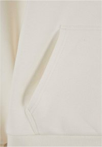 Light beige hoodie featuring a kangaroo pocket, ribbed cuffs and hem, with a soft, textured fabric and clean stitching details.